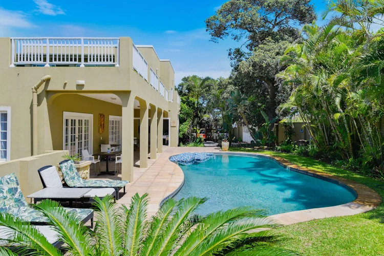 caza beach guest house tuin met zwembad.webp